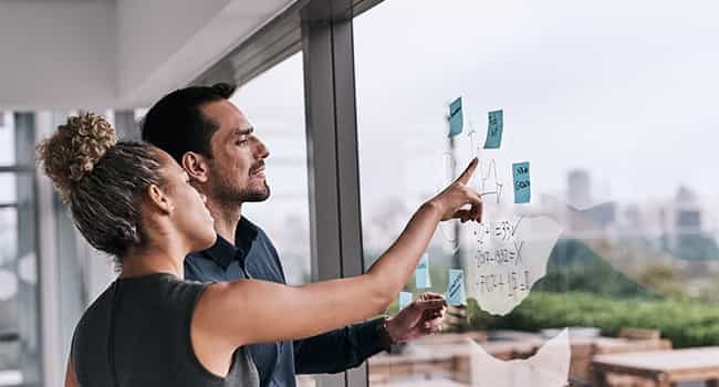 real estate colleagues discuss sticky notes on an office window